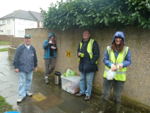 FotS volunteers seek temporary shelter from the rain under some overhanging shrubbery. Yikes! Cut it back at once!